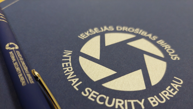 Attēls ar Iekšējās drošības biroja logo un zilu pildspalvu, uz kuras arī ir Iekšējās drošības biroja logo.