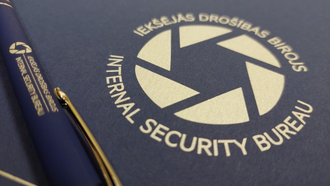 Attēls ar Iekšējās drošības biroja logo un zilu pildspalvu, uz kuras arī ir Iekšējās drošības biroja logo.