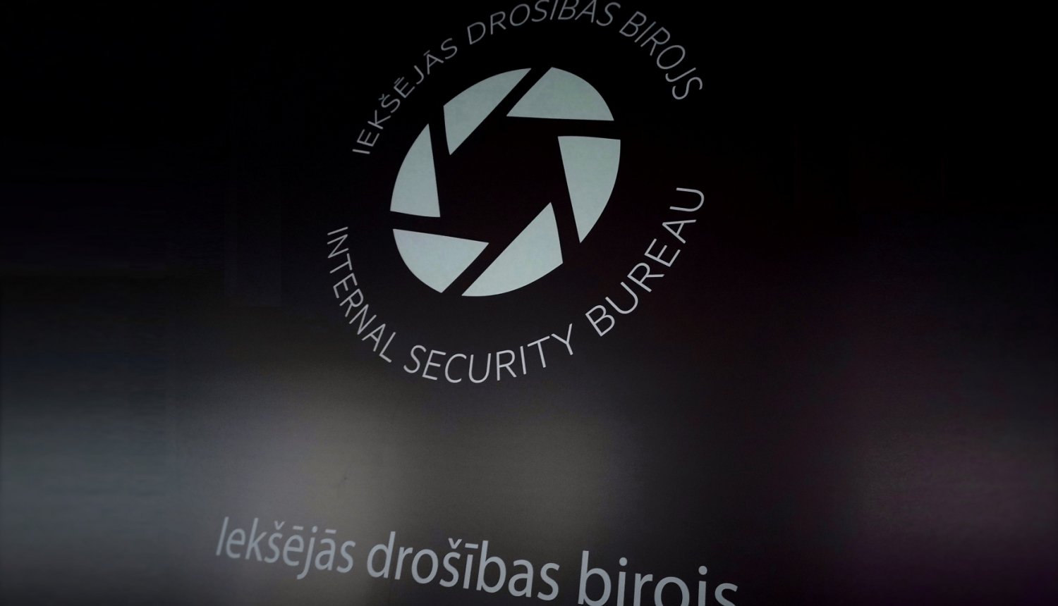 Attēls ar Iekšējās drošības biroja logo uz tumša fona