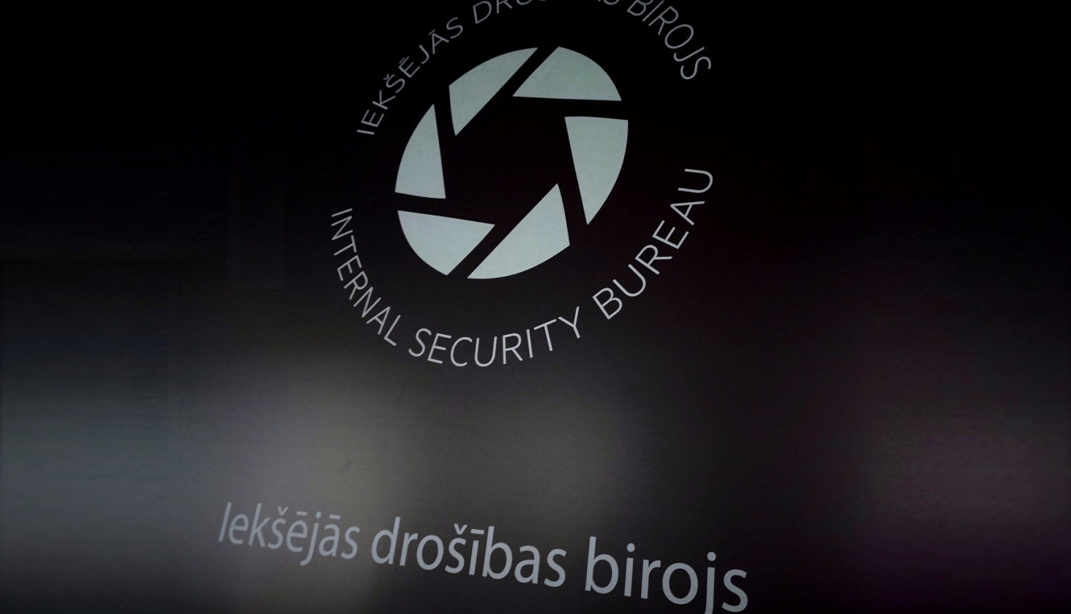 Attēls ar Iekšējās drošības biroja logo uz tumša fona
